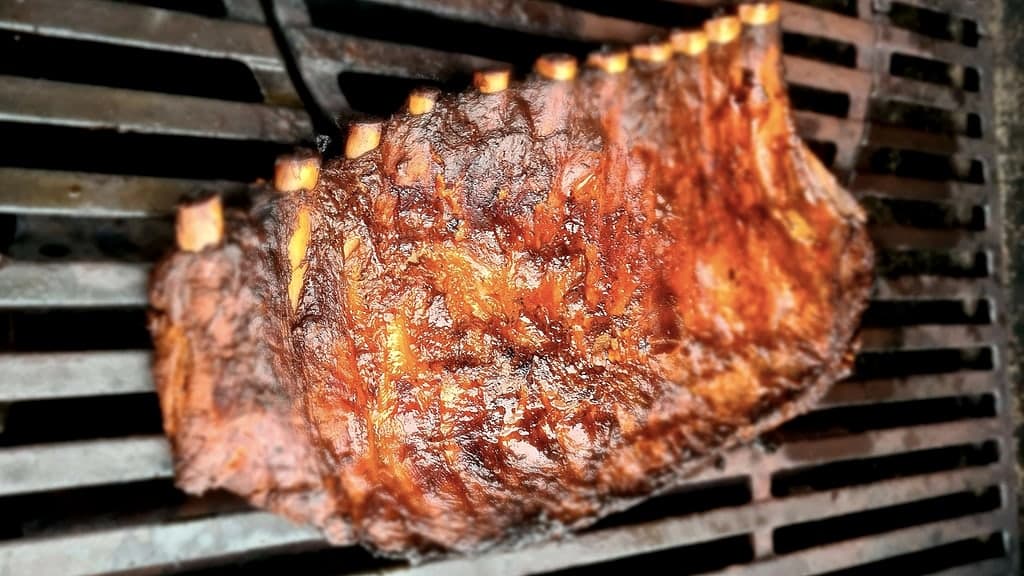Glasierte Spareribs mit freigelegten Knochenenden auf dem Grillrost, karamellisierte Oberfläche — Symbolbild