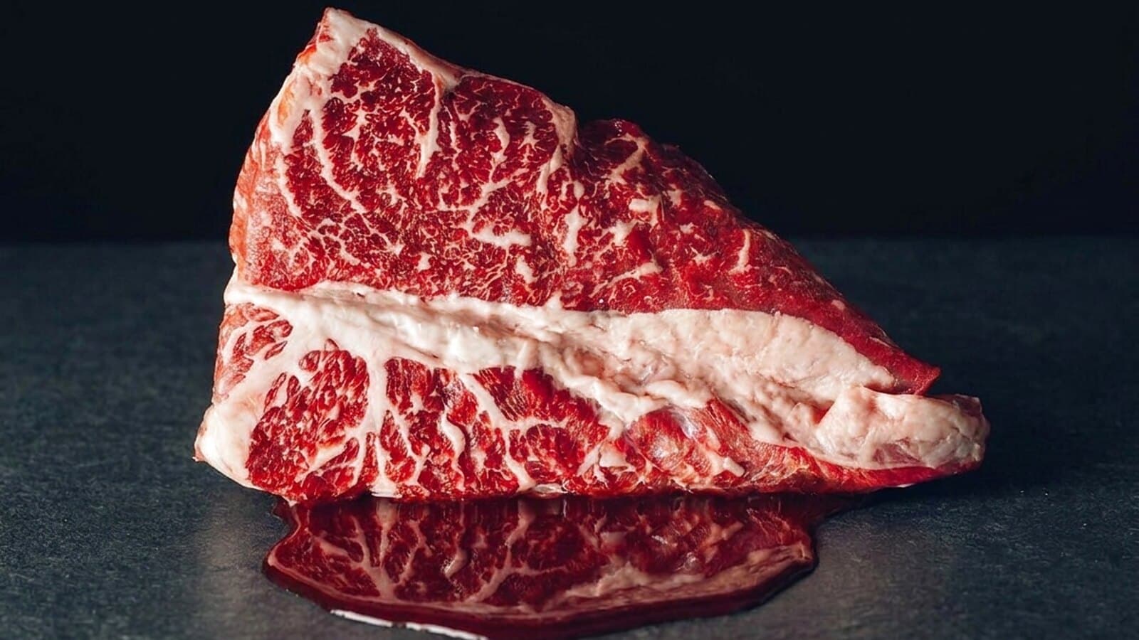 Rohes Steak auf dunklem Schiefer mit austretendem rotem Fleischsaft