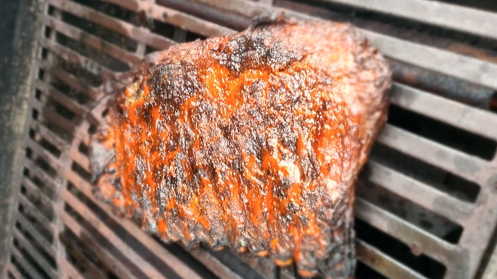 Spareribs nach der Räucherphase: dunkle, ledrige Bark auf dem Grillrost, noch ohne Glasur